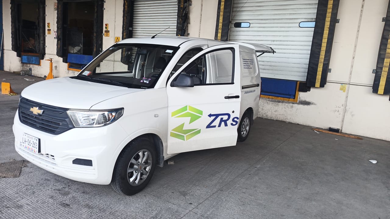 Camioneta rotulada de ZR Soluciones, con el logotipo verde a la vista, estacionada en un andén de carga